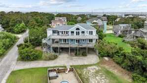 A large, two-story house with a prominent front porch and a swimming pool in the backyard. - 7135-Our Blue Haven - Waves Retreat | Pool | 300 Yards to Beach (Waves)