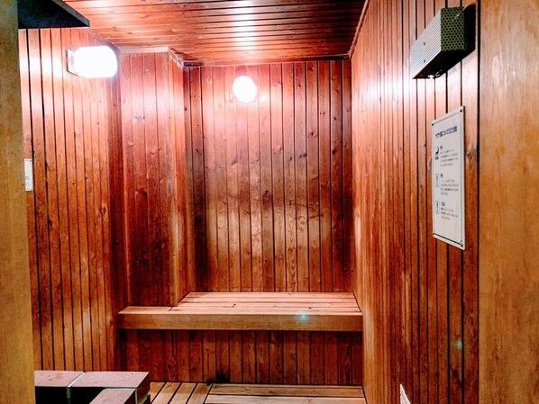 A sauna room with wooden walls and a bench.