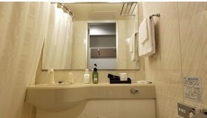 Un baño con lavamanos, espejo y toallero.