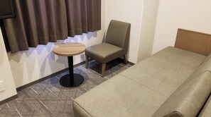 Cozy retreat with a single bed, round table, and comfortable chair.