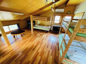 Cozy cabin with a central table, bunk bed, and desk area for work or study.