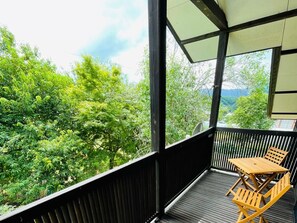 Enjoy the serene view of lush green trees from this balcony.