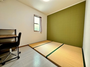 A room with tatami mats, a desk, and a chair.