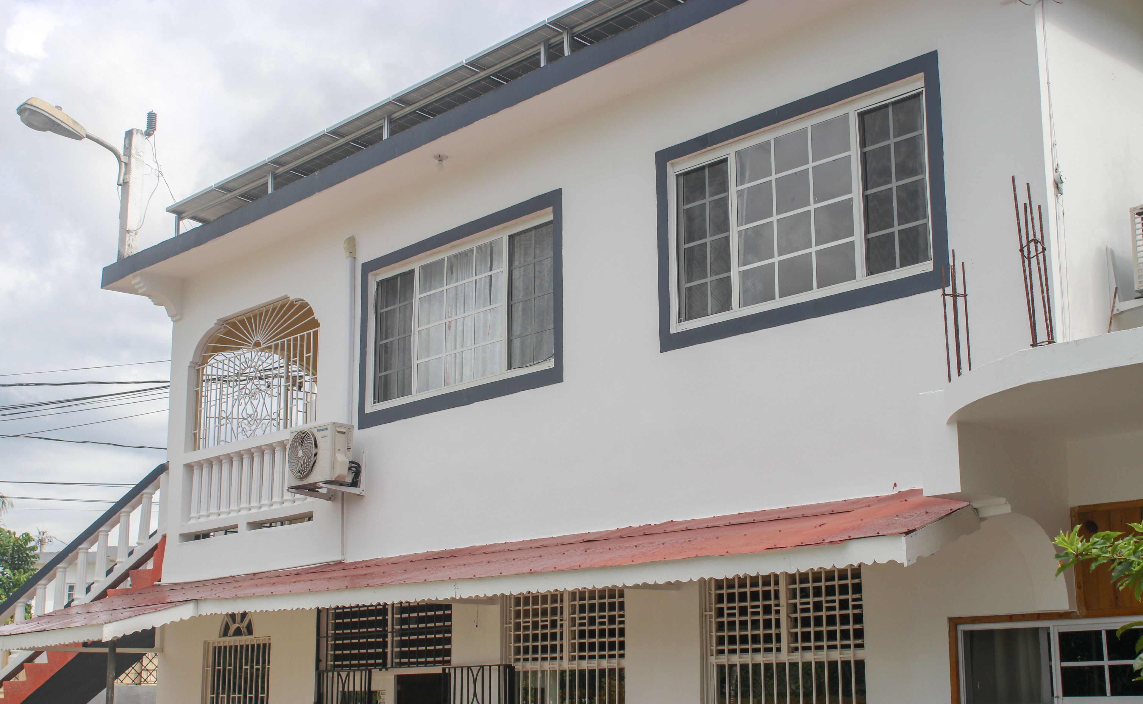 A two-story building with a balcony, large windows, and a red roof.