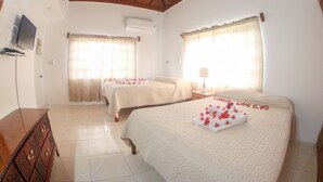 A hotel room with two beds, a wooden dresser, a television, and a ceiling fan. - Van Villa Holidays (Negril)