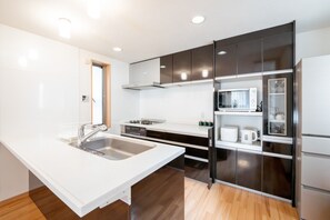 Een koelkast, een magnetron, een kookplaat, kookgerei, borden en bestek