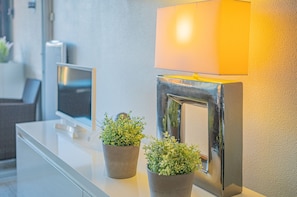 Ein Empfangsschalter mit Flachbildfernseher, einer Wandlampe und zwei Zimmerpflanzen.