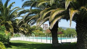 A pool area surrounded by palm trees and a building in the background. - L'épuisette à Cassis by Winkyhouse (Cassis)
