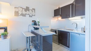A modern kitchen with a central island, stainless steel appliances, and dark cabinetry. - L'épuisette à Cassis by Winkyhouse (Cassis)