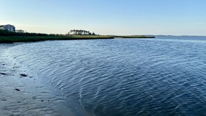 A calm body of water with a sandy beach and a line of trees in the distance. - Bethany Bay Beach Oasis, 4 Bed 3 bath, pool, golf, kayak, Ocean View (Ocean View)