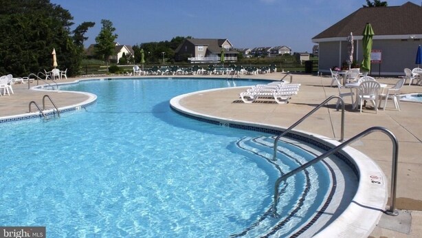 A swimming pool with multiple lanes, lounge chairs, and umbrellas. - Bethany Bay Beach Oasis, 4 Bed 3 bath, pool, golf, kayak, Ocean View (Ocean View)