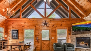 A cozy cabin interior with a wooden interior, a fireplace, and a star decoration on the wall. - Grand Mountain View Lodge By Ghosal Lodging (Sevierville)