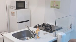 Eine kleine Küchenzeile mit Spüle, Mikrowelle, Herd und Kühlschrank.