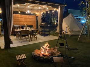 Enjoy al fresco dining and relaxation in this patio area, featuring a grill, fire pit, and comfortable seating for two.