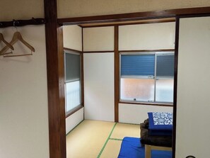 Traditional Japanese-style room with tatami flooring and shoji screens, featuring a small bed and a wooden chair.