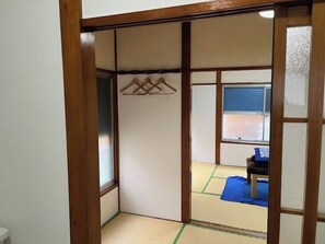 Experience traditional Japanese style in this serene room featuring a futon bed, wooden chair, and tatami flooring.