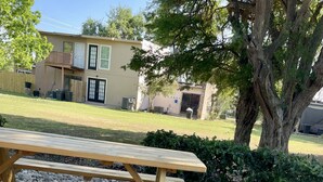 A wooden picnic table in a residential area with a bird on the ground.