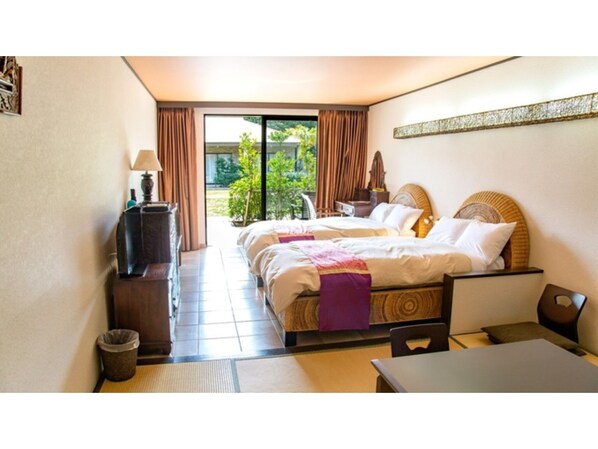 Habitación de hotel con cama, escritorio, silla, lámpara, basurero y vista al exterior.