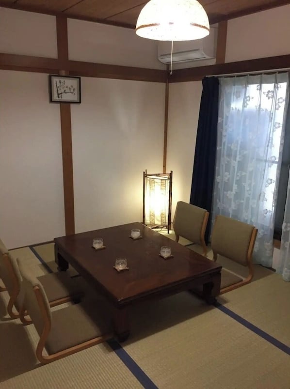 A traditional Japanese-style room with tatami flooring, a low wooden table, and four chairs.