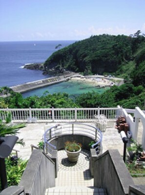 Enjoy unobstructed views of the coastline from this viewing area with a bench and potted plant.