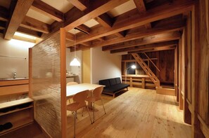 Cozy dining area with a table for two, a sofa, and a staircase leading to an upper level.