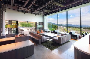 Relax in the spacious lounge area with sofas, chairs, and a coffee table, surrounded by expansive views of the scenic landscape.