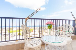 Enjoy the breathtaking coastal view from this balcony, featuring a round table and two comfortable chairs.