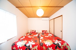 Une chambre avec deux lits, un plafond en bois, une fenêtre et un appareil de climatisation.