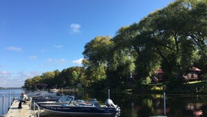 Un quai où sont amarrés des bateaux, une jetée en bois et une rangée de cabanes surmontées d’un toit rouge.