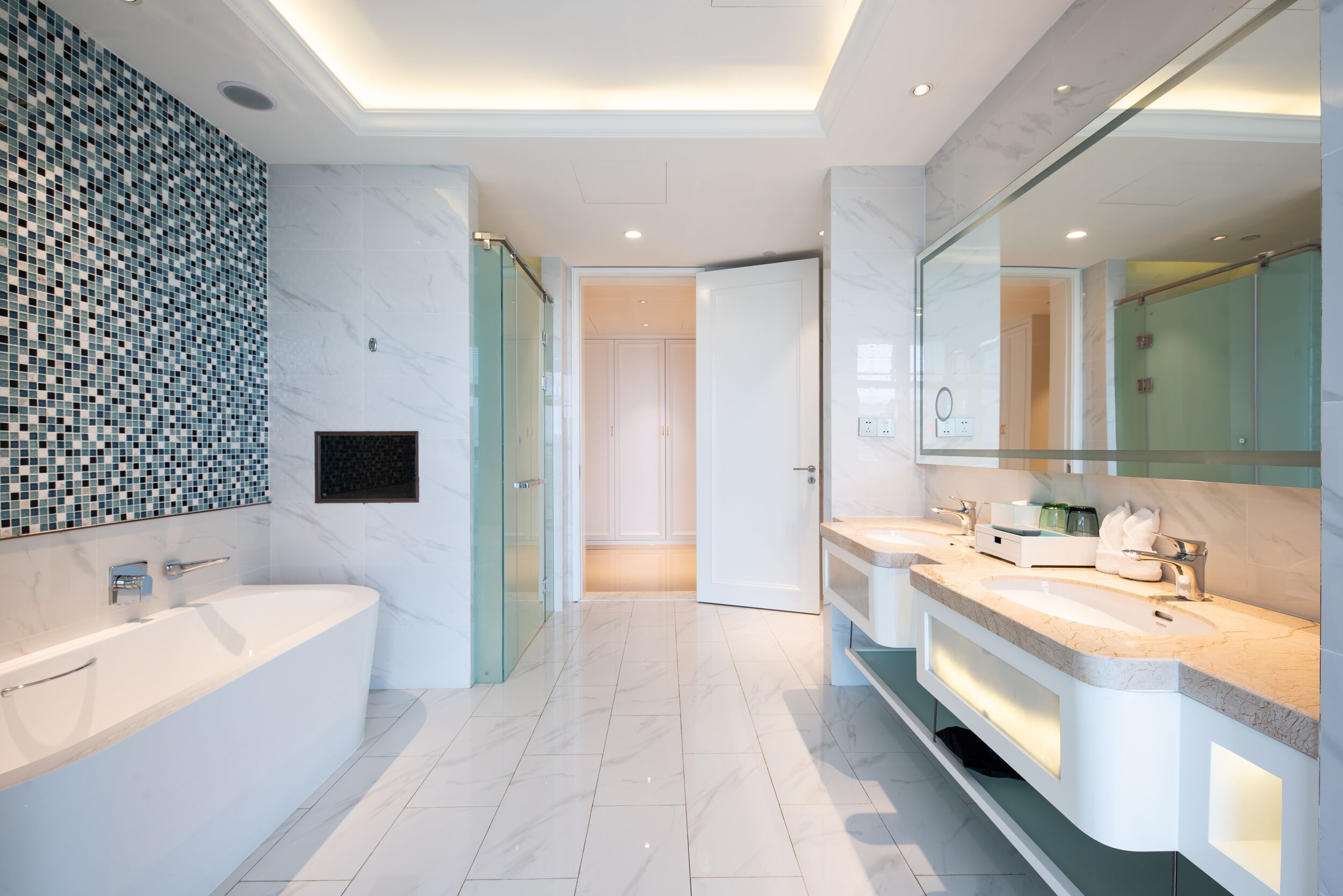 Ein modernes Badezimmer mit einer großen Badewanne, zwei Waschbecken und einer Duschkabine aus Glas.