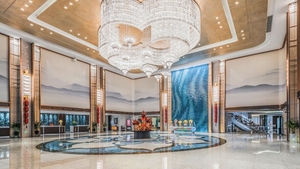 A spacious lobby with a large chandelier, a reception desk, and a decorative fountain. - Wuhu Suning Universal Hotel (Wuhu)