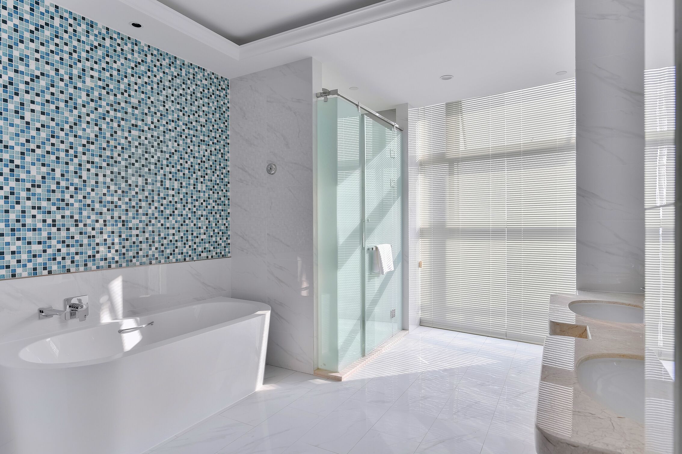 A modern bathroom with a large bathtub, a glass shower enclosure, and a tiled wall.