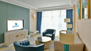 A modern hotel room with a flat-screen TV, a sofa, a round coffee table, and a cabinet. - Wuhu Suning Universal Hotel (Wuhu)