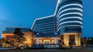 A modern hotel with a curved facade, large glass windows, and a well-lit entrance. - Wuhu Suning Universal Hotel (Wuhu)