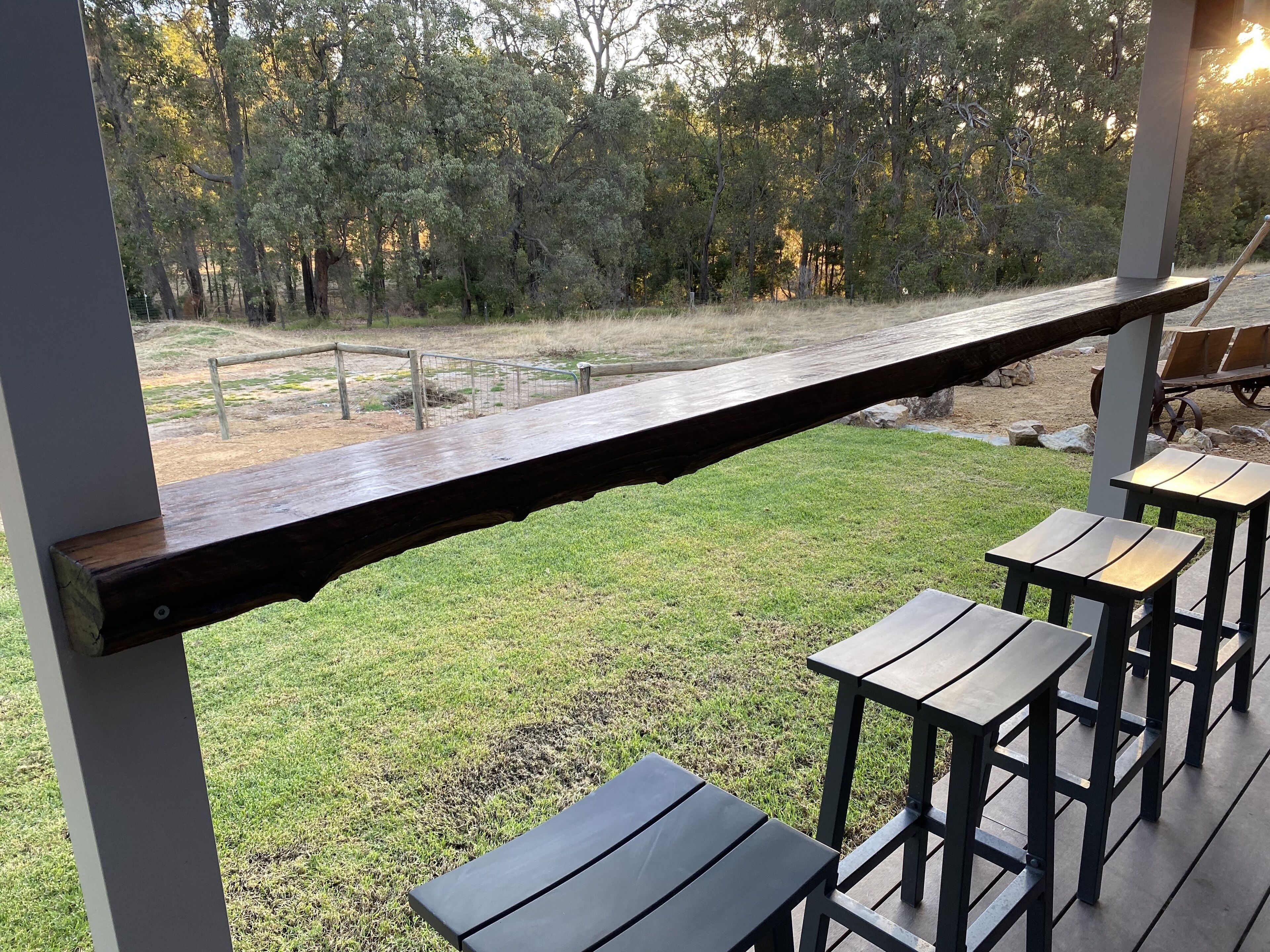 A wooden deck with a metal railing overlooking a grassy area with trees.