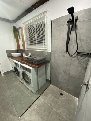 A compact laundry room with a washing machine, dryer, and a small sink.