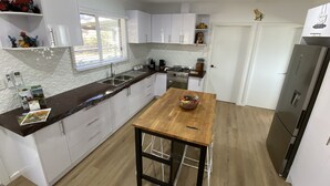 A modern kitchen with white cabinets, a wooden table, and a stainless steel refrigerator. - This Luxury Cabin is a true country retreat (Lowden)