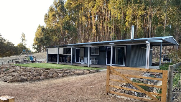 A modern house with a covered patio, a swing set, and a stone wall. - This Luxury Cabin is a true country retreat (Lowden)