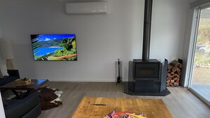 A living room with a TV, a fireplace, a sofa, and a wooden floor. - This Luxury Cabin is a true country retreat (Lowden)