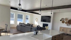 A modern kitchen with a large island, built-in appliances, and a dining area with a sofa and chairs. - Brand New Park City Home! (Park City)