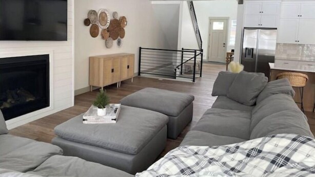 A modern living room with a fireplace, grey sofa, and a staircase leading to the kitchen. - Brand New Park City Home! (Park City)