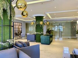 A modern lobby with a green wall, plush seating, and gold spherical lights.