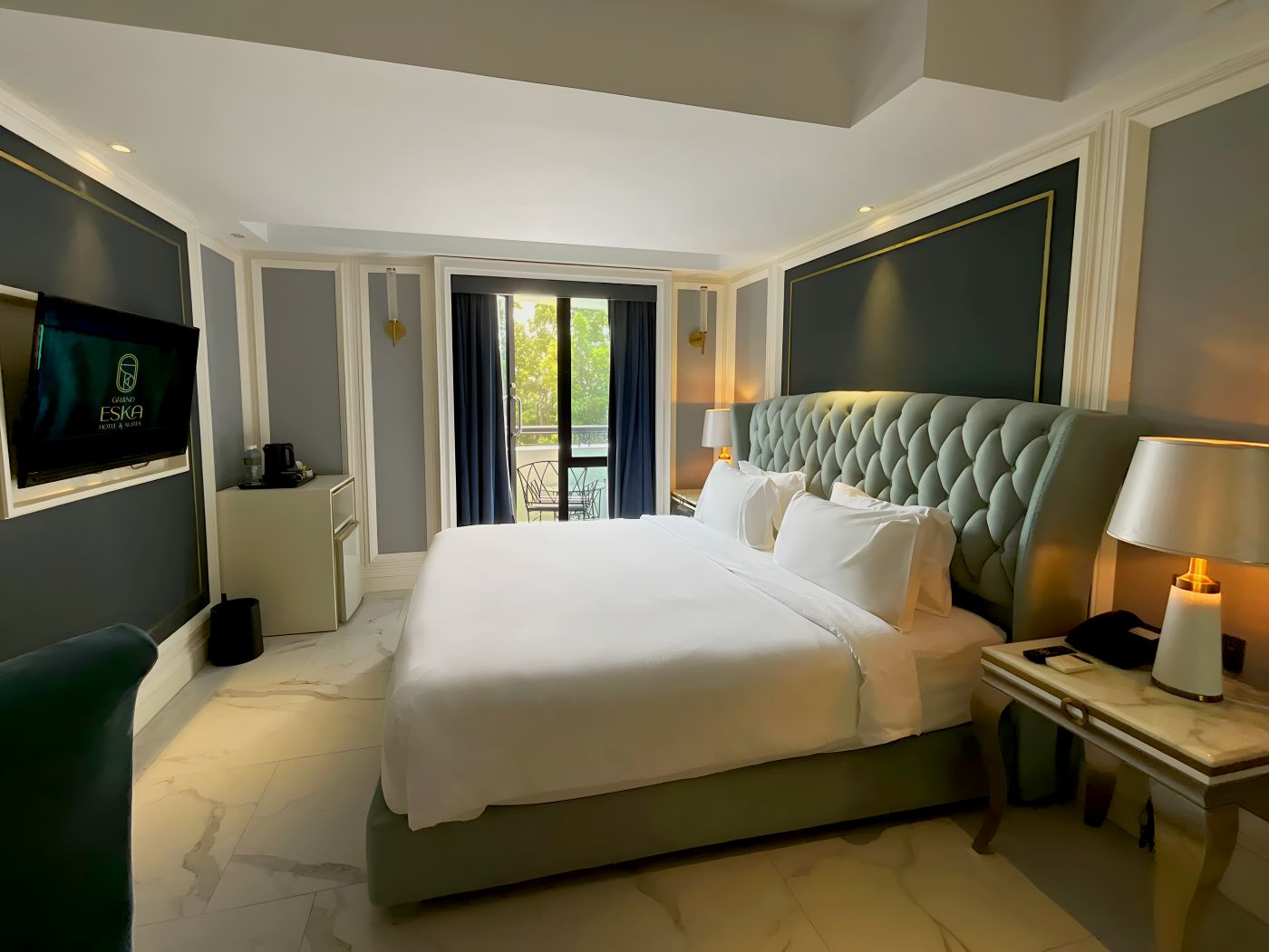Habitación de hotel con una cama grande, televisión, escritorio y vista al exterior.