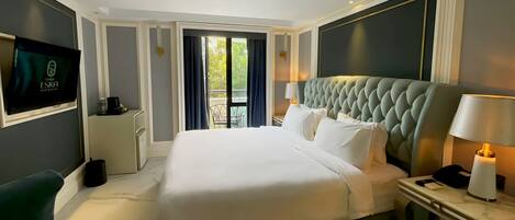 Habitación de hotel con una cama grande, televisión, escritorio y vista al exterior.