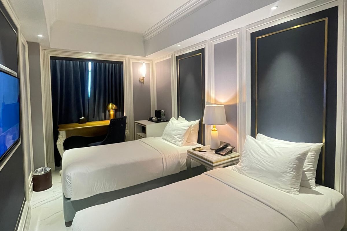 A hotel room with two beds, a TV, a desk, and a chair.