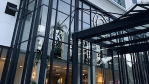 A modern building with large glass windows and a tower with a spire. - Grand Eska Hotel & Suite  (Batam)