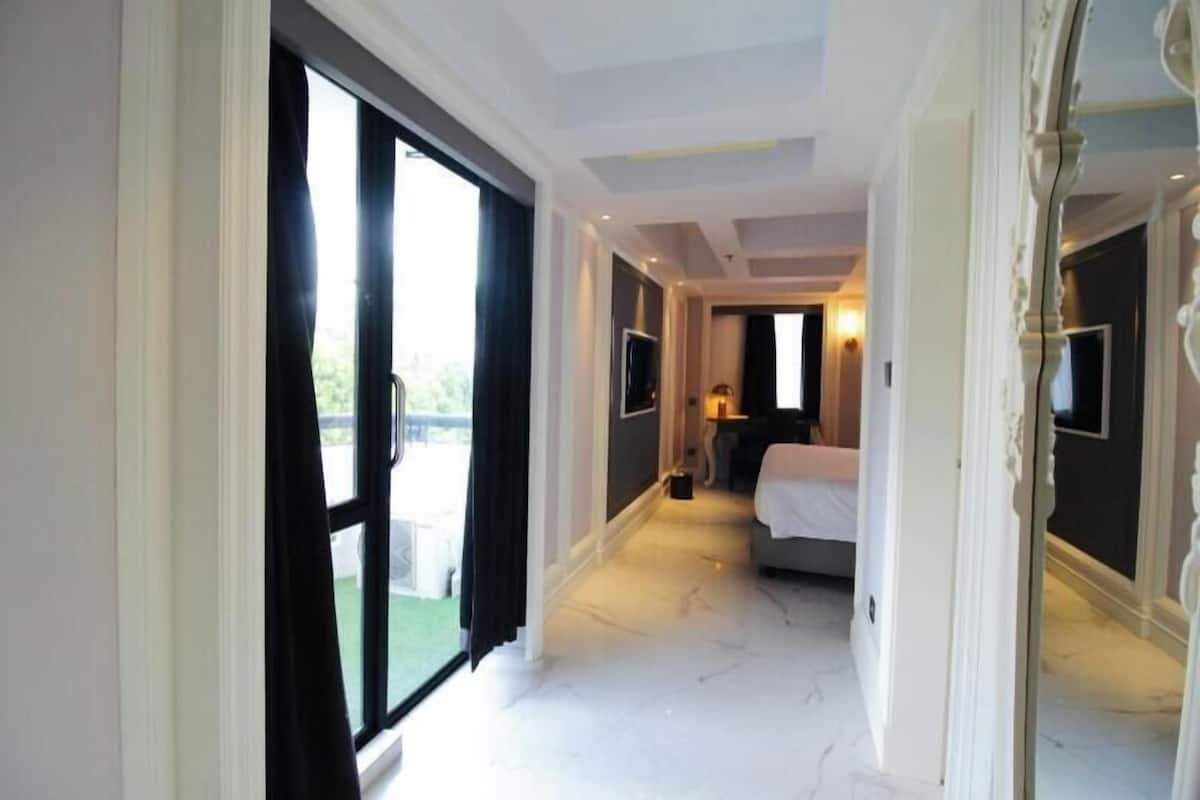 A hotel room with a large bed, a TV, and a view of the outdoors through a sliding door.