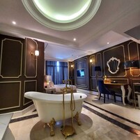 Un bagno di lusso con una vasca da bagno indipendente, un mobile toilette con specchio e un'area salotto con una poltrona e un tavolo.