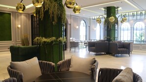 A modern lounge area with plush seating, a round table, and decorative greenery. - Grand Eska Hotel & Suite  (Batam)