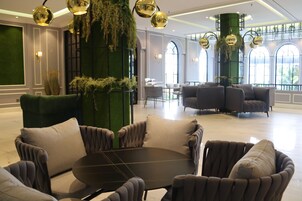 A modern lounge area with plush seating, a round table, and decorative greenery.